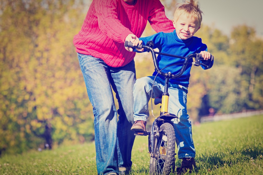 father teaches son to ride bicycle